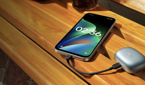 Teléfono Redmi 17 4G conectado mediante un cable USB-C a un estuche de auriculares inalámbricos sobre una mesa de madera.