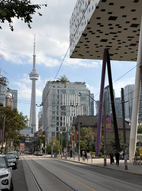 Calle urbana con vías de tranvía en Toronto, la Torre CN al fondo y el edificio Sharp Centre for Design a la derecha.