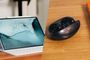 Tableta Huawei MatePad Air con teclado y auriculares inalámbricos FreeBuds Neo en su estuche de carga sobre una mesa de madera.