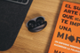 Estuche de carga abierto de los auriculares Huawei FreeBuds Neo sobre una mesa de madera junto a un libro naranja.