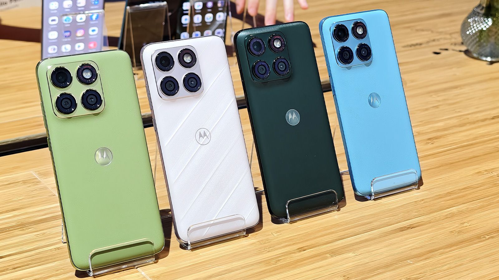 Cuatro smartphones Motorola edge 70 plus alineados en colores verde, blanco, negro y azul sobre una mesa de madera.