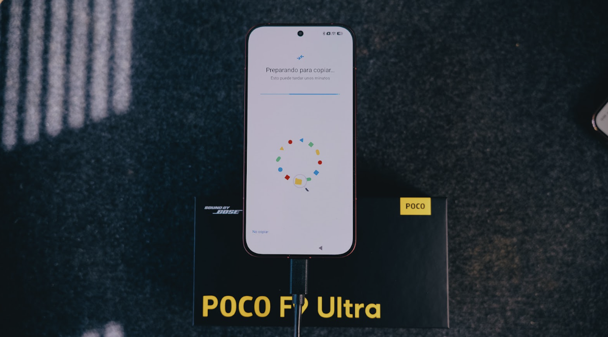 Proceso de configuración inicial en la pantalla de un POCO F9 Ultra conectado por cable sobre su caja original.