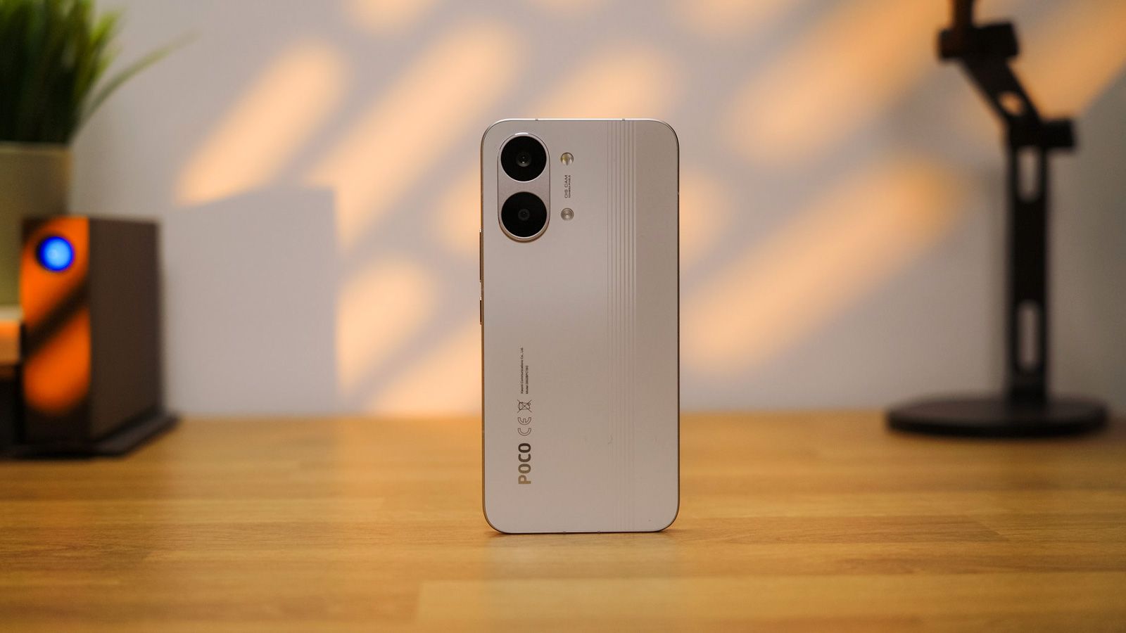 Parte trasera del smartphone POCO X8 Pro Max en color blanco con su doble módulo de cámara vertical sobre una mesa de madera.