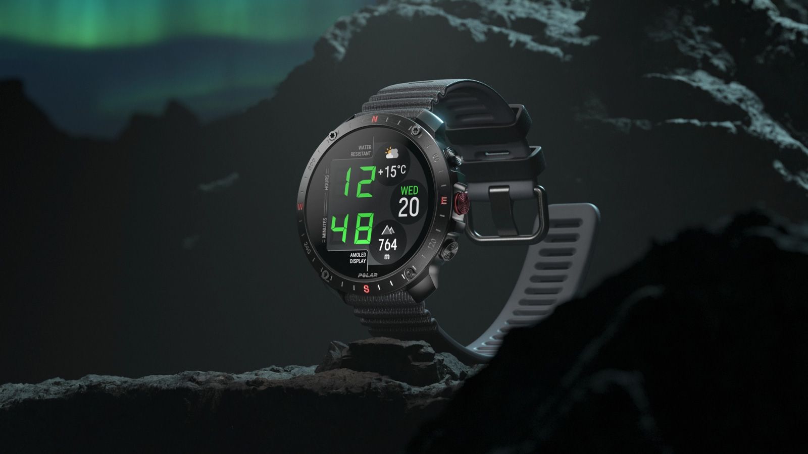 Reloj inteligente Polar Grit X2 Pro Titan sobre una roca bajo una aurora boreal.