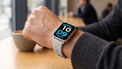 Reloj inteligente Redmi Watch 6 Active con esfera digital en la muñeca de un usuario en una cafetería.