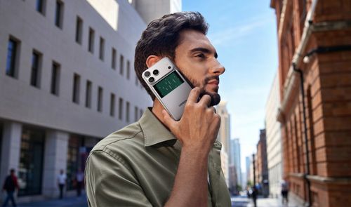 Hombre utilizando un iPhone con la batería magnética UGREEN MagFlow Pro acoplada mientras camina por la calle.
