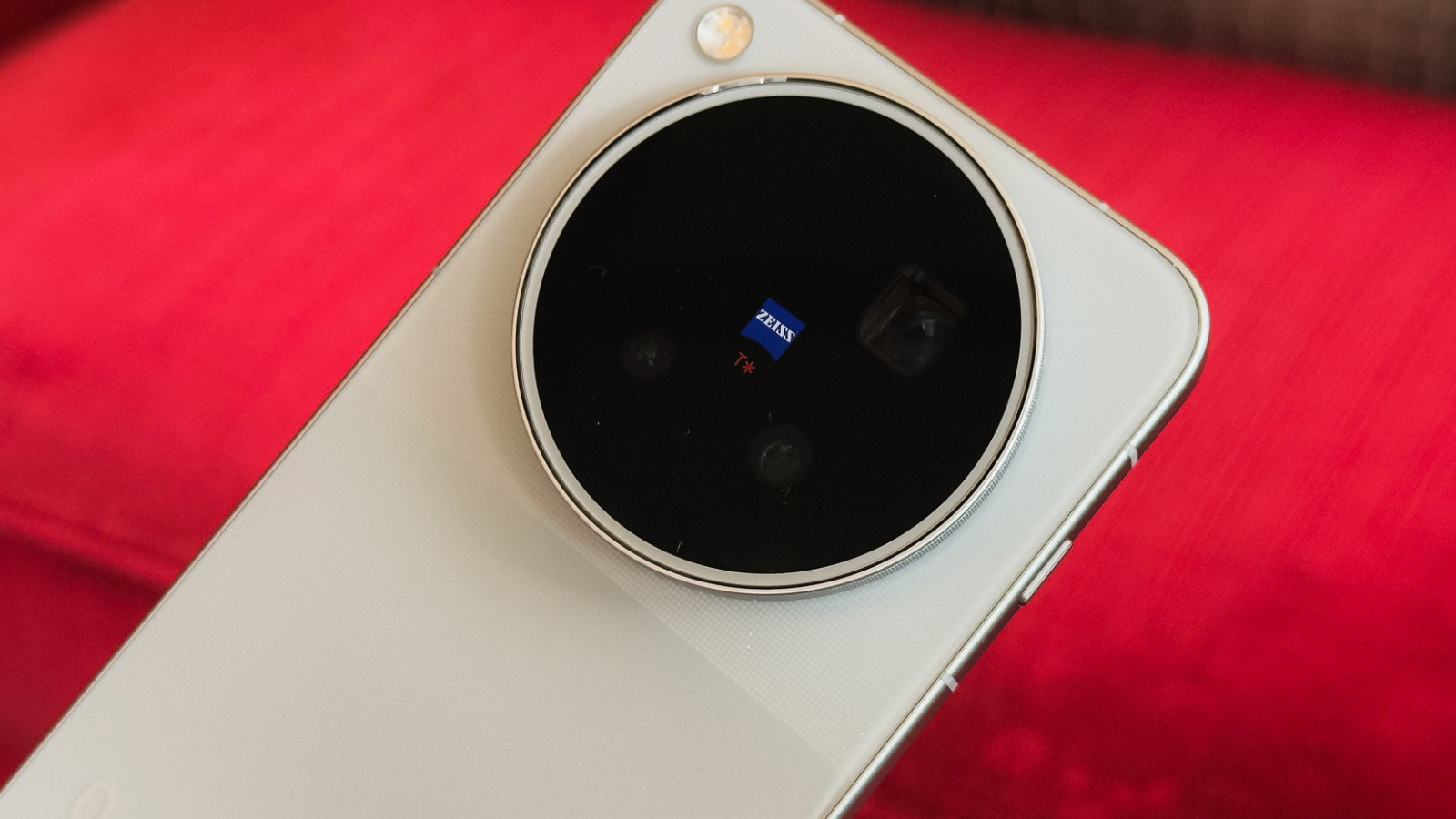 Primer plano del módulo de cámara circular del vivo x500 con ópticas Zeiss sobre fondo rojo.