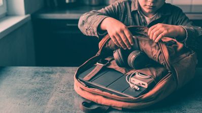 Niño metiendo en su maleta diferentes dispositivos para el colegio