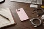 iPhone 15 Plus en color rosa sobre una mesa de madera junto a cables de carga y una libreta abierta.