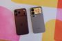 Vista trasera de un iPhone 18 Pro Max en color granate junto a un Xiaomi 18 Pro Max con pantalla secundaria en el módulo de cámaras sobre una superficie de colores.