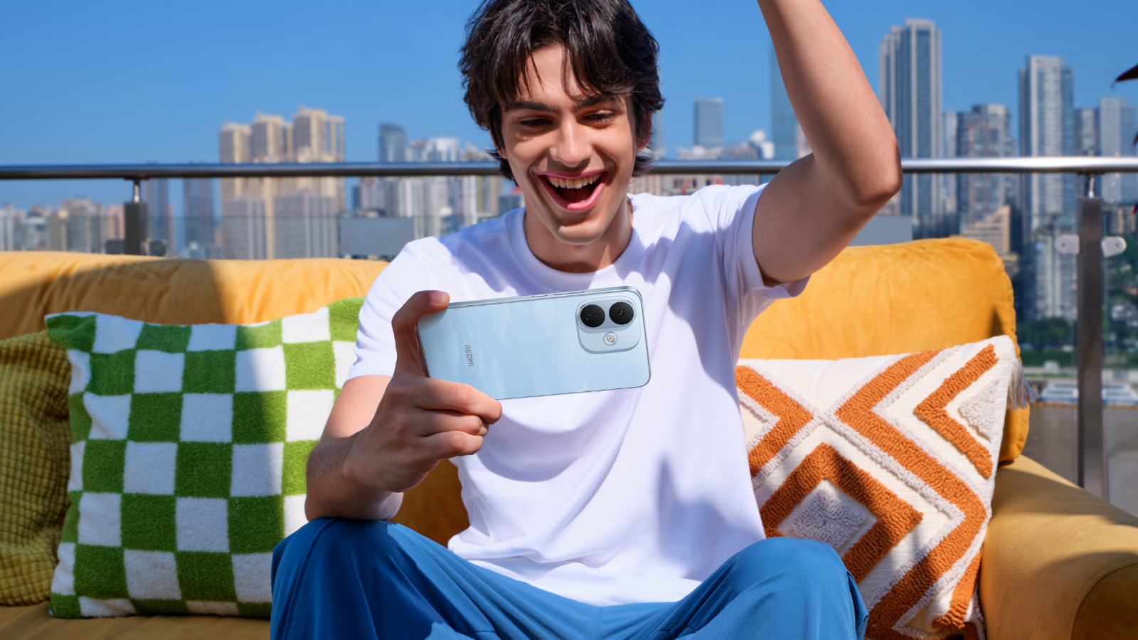 Joven sentado en una terraza sosteniendo en horizontal un REDMI Note 17 Pro 5G mientras celebra una partida.