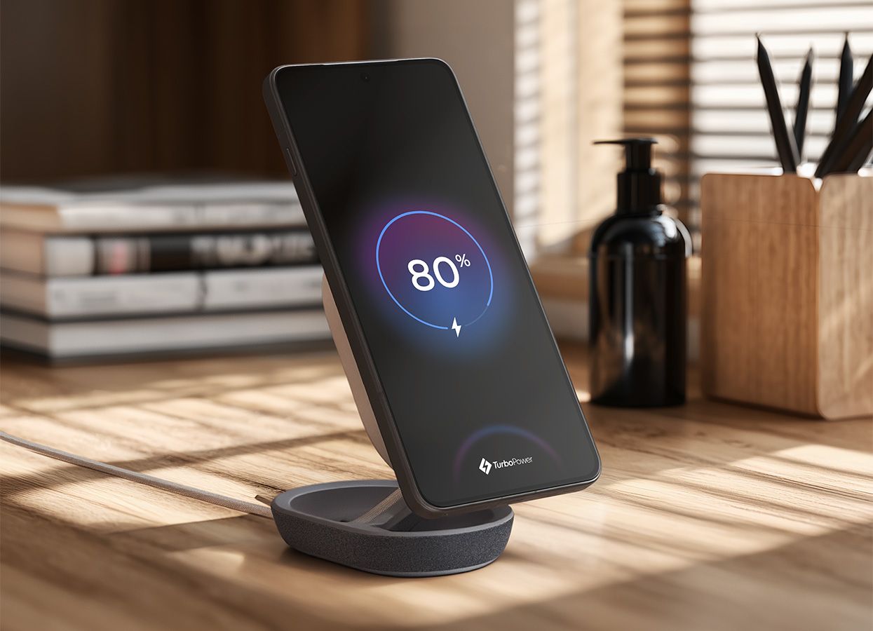 Teléfono móvil cargando verticalmente en el soporte Moto Snap Wireless Charger sobre un escritorio de madera.