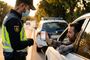 Conductor mostrando la pantalla de su móvil con el carnet de conducir digital a un agente de policía en un control de carretera.