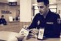 Agente de Policía Nacional señalando un documento informativo junto a un teléfono móvil con la aplicación miDNI abierta.