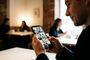 Primer plano de un hombre usando la aplicación de TikTok en un smartphone en una cafetería.