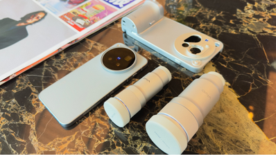 Perspectiva cenital del vivo x500 junto a una funda con grip fotográfico y dos lentes externas sobre una mesa de mármol.