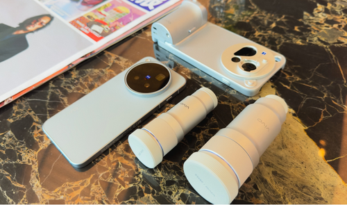 Perspectiva cenital del vivo x500 junto a una funda con grip fotográfico y dos lentes externas sobre una mesa de mármol.
