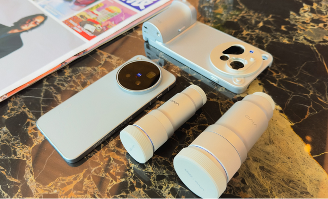 Perspectiva cenital del vivo x500 junto a una funda con grip fotográfico y dos lentes externas sobre una mesa de mármol.