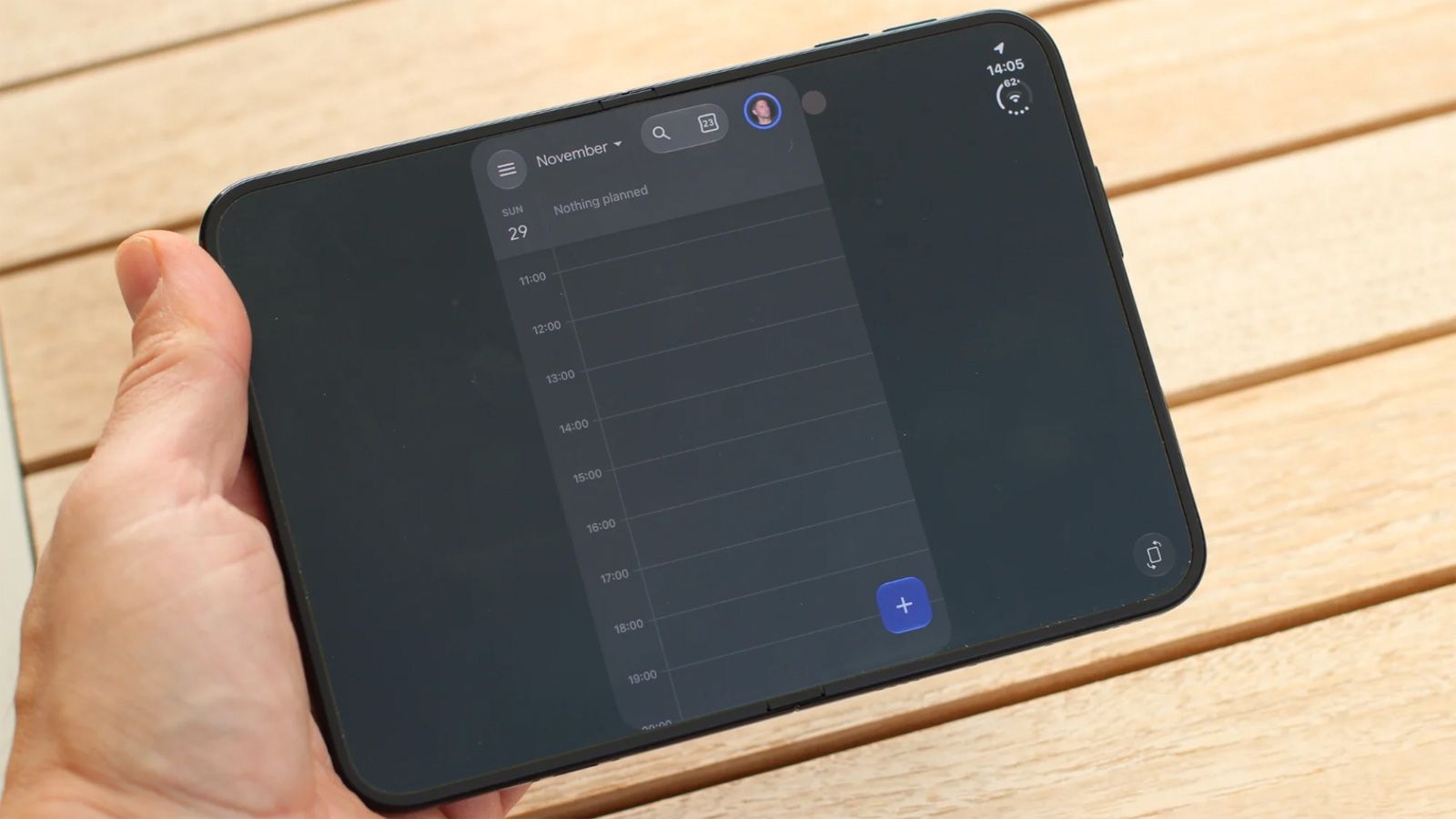 Interfaz de una aplicación de calendario con problemas de escalado en la pantalla de un iPhone Duo sostenido con la mano.