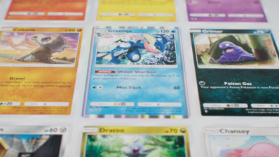 Primer plano de varias cartas de Pokémon coleccionables, incluyendo a Greninja, Cubone y Grimer sobre una superficie blanca.