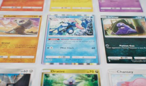 Primer plano de varias cartas de Pokémon coleccionables, incluyendo a Greninja, Cubone y Grimer sobre una superficie blanca.