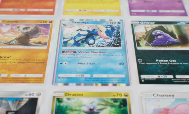 Primer plano de varias cartas de Pokémon coleccionables, incluyendo a Greninja, Cubone y Grimer sobre una superficie blanca.