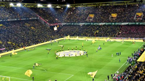 Vista panorámica nocturna de las gradas y el césped del Signal Iduna Park durante la previa de un partido del Borussia Dortmund.