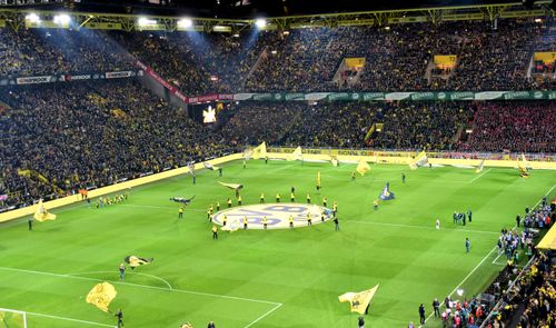 Vista panorámica nocturna de las gradas y el césped del Signal Iduna Park durante la previa de un partido del Borussia Dortmund.
