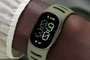 Reloj inteligente Google Fitbit Edge con correa verde oliva en la muñeca, mostrando la hora y datos de actividad física.