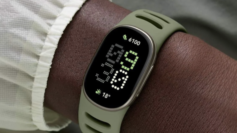 Reloj inteligente Google Fitbit Edge con correa verde oliva en la muñeca, mostrando la hora y datos de actividad física.
