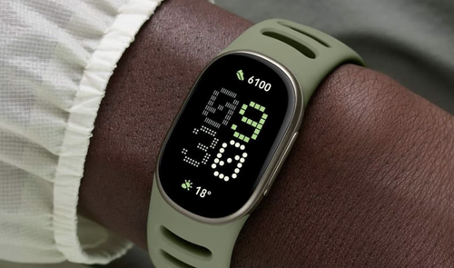 Reloj inteligente Google Fitbit Edge con correa verde oliva en la muñeca, mostrando la hora y datos de actividad física.