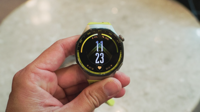 Primer plano de un Huawei Watch GT7 con correa de color verde lima sostenido por una mano.
