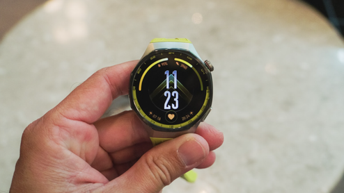Primer plano de un Huawei Watch GT7 con correa de color verde lima sostenido por una mano.