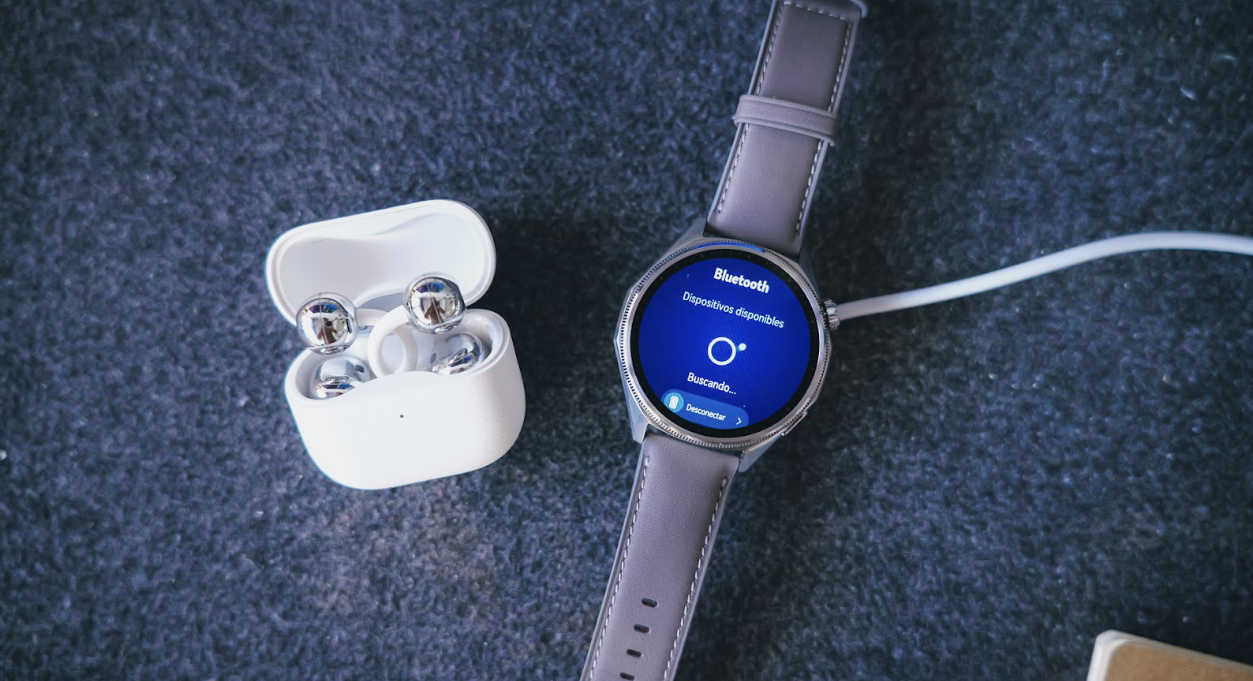 Reloj Huawei Watch GT7 con menú de búsqueda de dispositivos Bluetooth junto a unos auriculares inalámbricos en su estuche.
