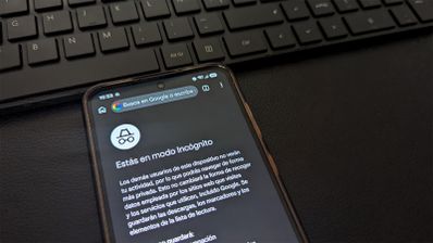 Pantalla de un teléfono móvil que muestra la interfaz del modo incógnito en el navegador de Google Chrome, situado junto a un teclado de ordenador.