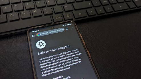 Pantalla de un teléfono móvil que muestra la interfaz del modo incógnito en el navegador de Google Chrome, situado junto a un teclado de ordenador.