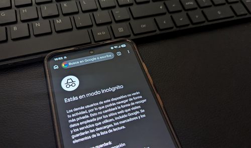 Pantalla de un teléfono móvil que muestra la interfaz del modo incógnito en el navegador de Google Chrome, situado junto a un teclado de ordenador.