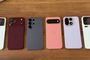 Seis smartphones de diferentes marcas y colores colocados en fila sobre una superficie de madera, mostrando sus módulos de cámara traseros.