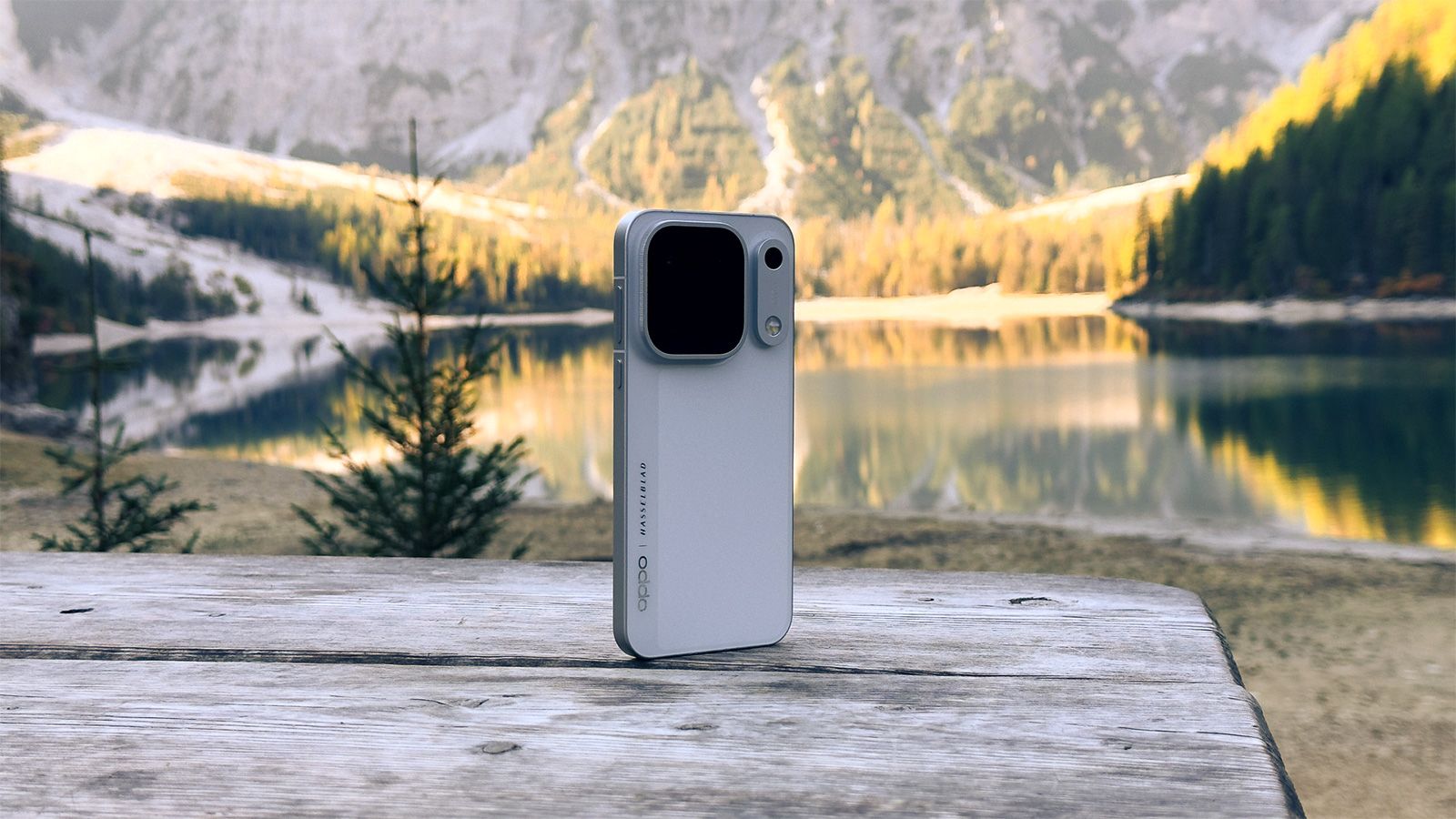Parte trasera de un teléfono OPPO Find X10 Pro Max sobre una mesa de madera con un lago y montañas de fondo.