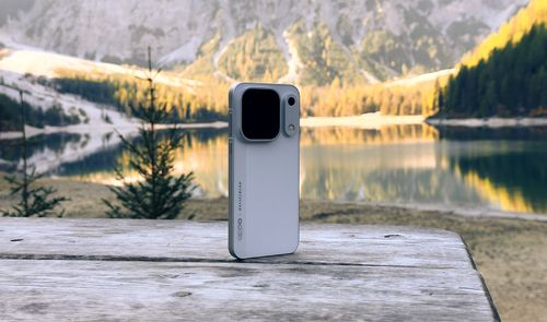 Parte trasera de un teléfono OPPO Find X10 Pro Max sobre una mesa de madera con un lago y montañas de fondo.