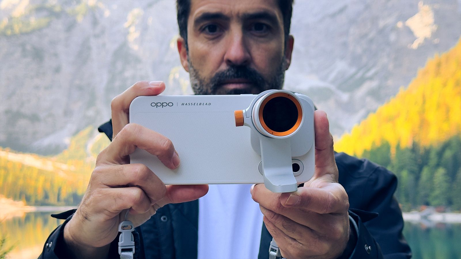 Primer plano de un hombre sujetando el OPPO Find X10 Pro Max en horizontal con un teleconvertidor acoplado a la cámara trasera.