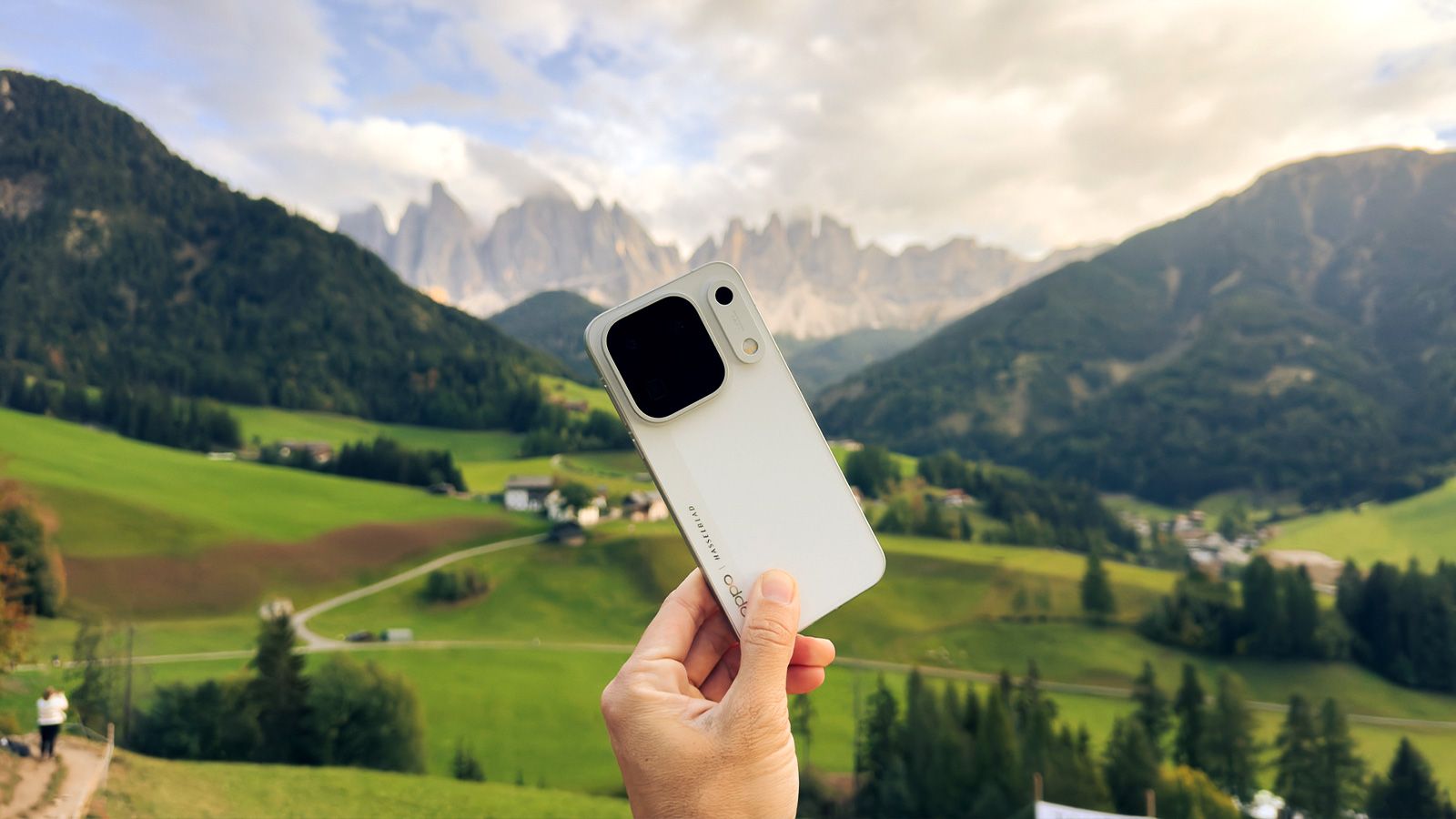 Trasera del OPPO Find X10 Pro en color blanco sostenido ante un valle de montaña con picos rocosos.