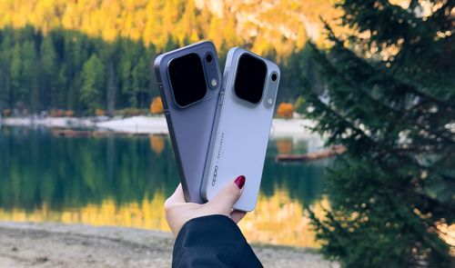 Parte trasera de dos teléfonos de la gama OPPO Find X10 Series sostenidos frente a un lago de montaña.