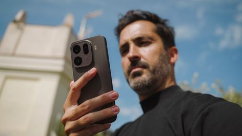 Primer plano del módulo de cámaras trasero del OPPO Find X9 sostenido por un hombre en exteriores.