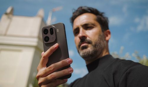 Primer plano del módulo de cámaras trasero del OPPO Find X9 sostenido por un hombre en exteriores.