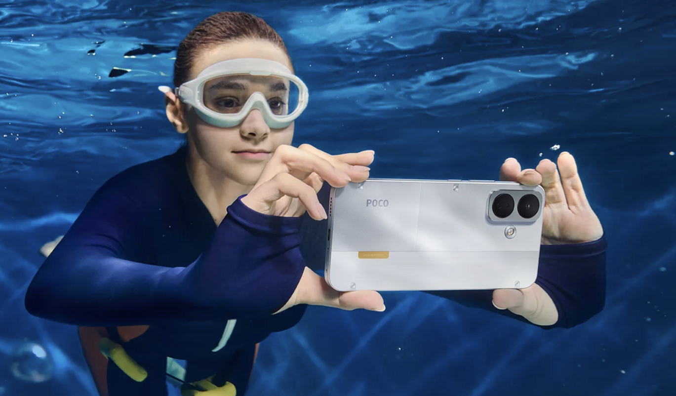Buceadora con gafas de natación sosteniendo un POCO X8 blanco bajo el agua.