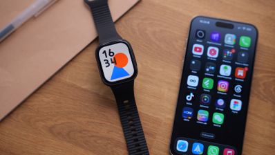 Reloj inteligente REDMI Watch 6 Lite con correa negra al lado de un teléfono móvil sobre una mesa de madera.