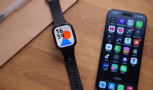 Reloj inteligente REDMI Watch 6 Lite con correa negra al lado de un teléfono móvil sobre una mesa de madera.