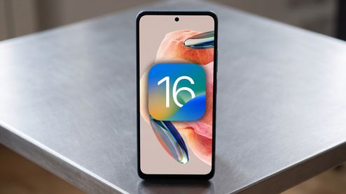 Teléfono Redmi Note 12 apoyado en una mesa con el logotipo del sistema operativo iOS 16 superpuesto en pantalla.