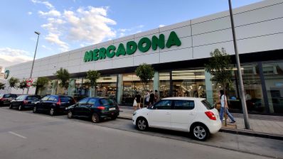 Fachada exterior de un supermercado Mercadona con clientes y vehículos aparcados